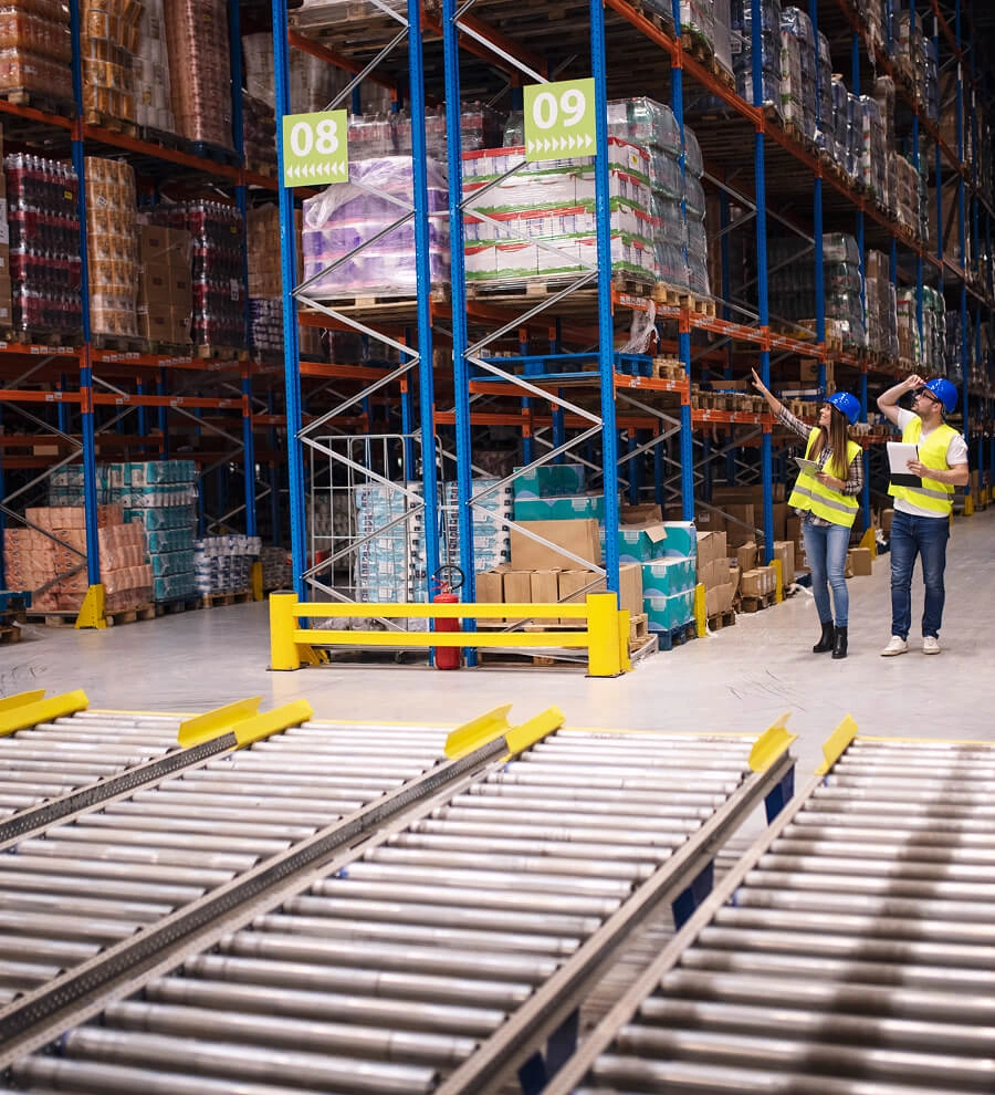 Refrigerated warehouse aisle with lot-labelled pallets on steel racking and ceiling evaporator units